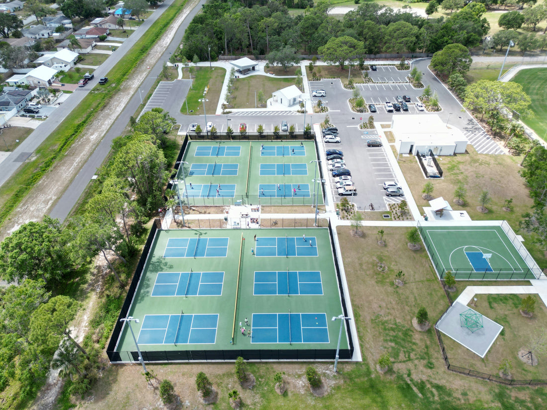 A drone shot of an outdoor pickleball court featuring blue and green courts in a park