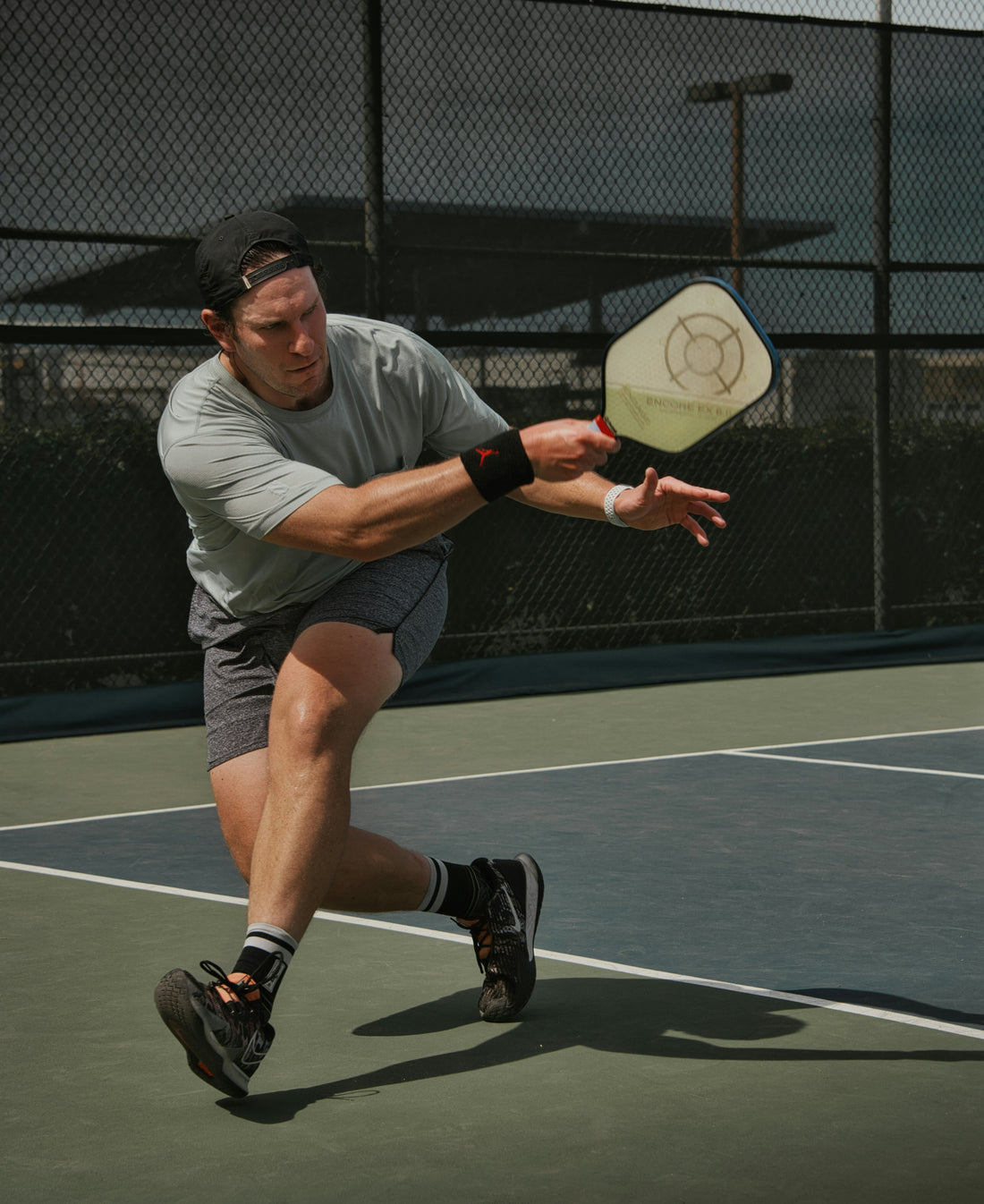 Man playing pickleball with a paddle out in front of him, as if he just hit a shot.